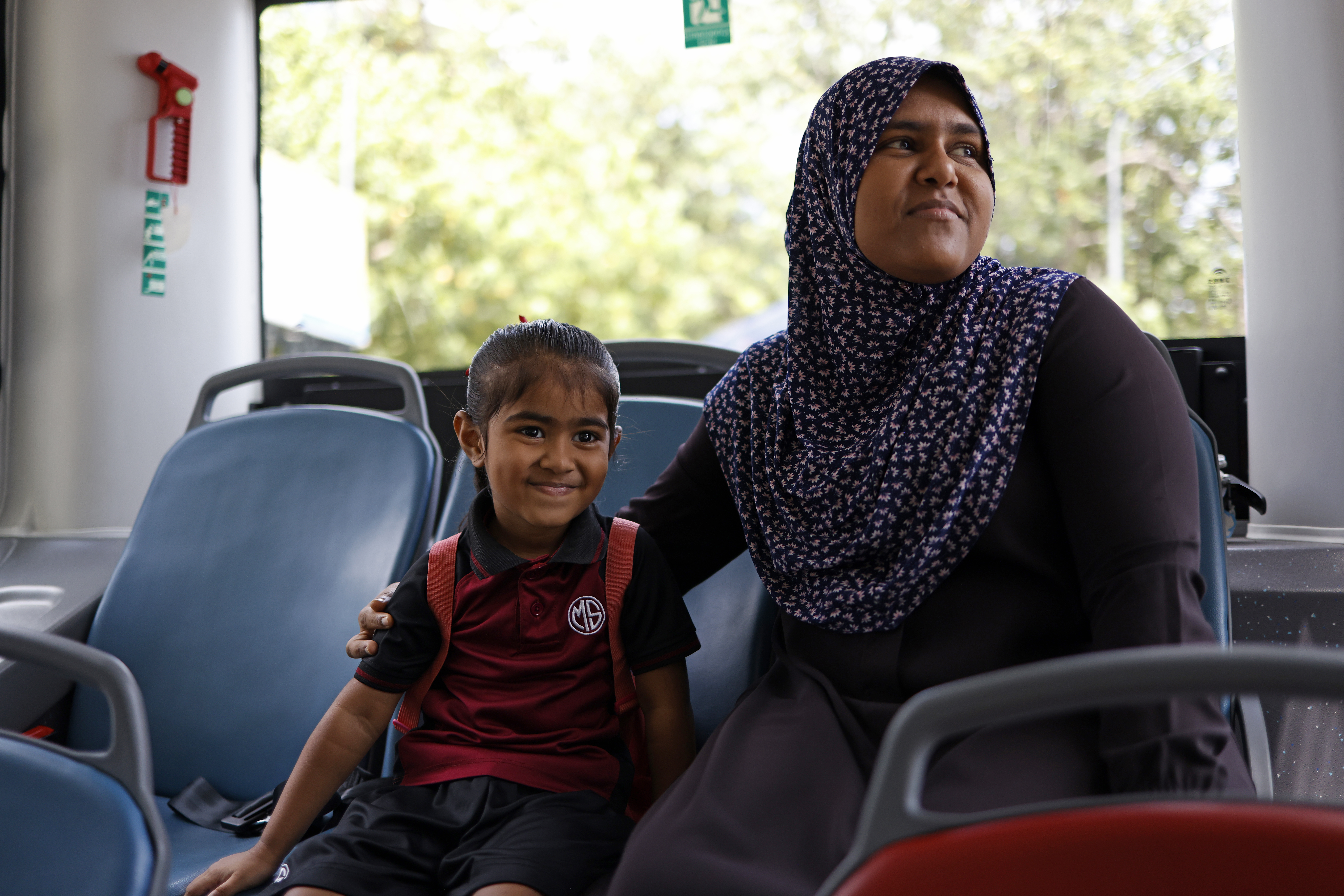 a woman and female child on board the ev bus, smiling