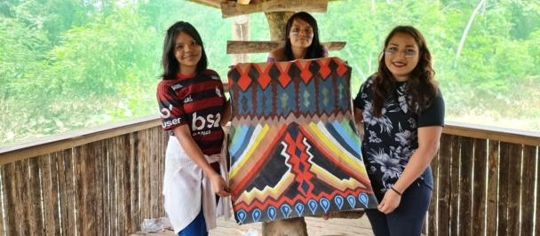 Three women demonstrate a native design