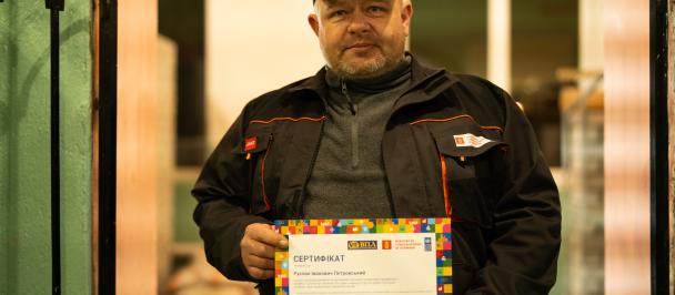 Man in baseball cap holds professional certificate
