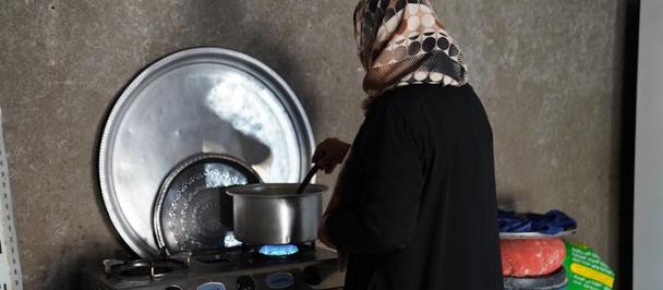 Woman in hijab cooks at stove